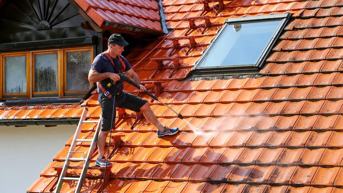 Close-up of a high-pressure water jet cleaning a tiled roof.